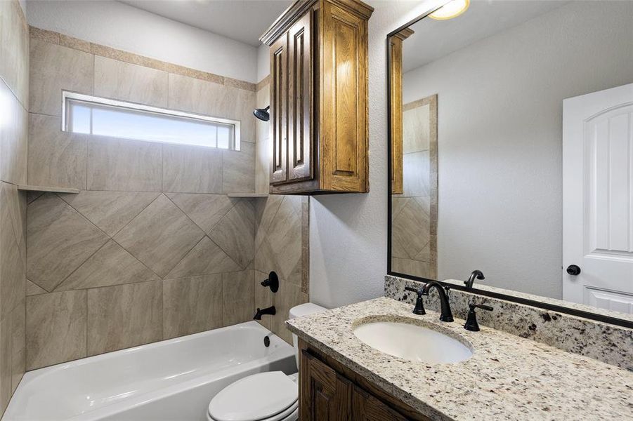 Full bathroom with tiled shower / bath combo, toilet, and vanity