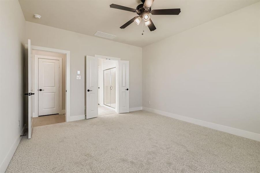 Unfurnished bedroom with light carpet and a ceiling fan