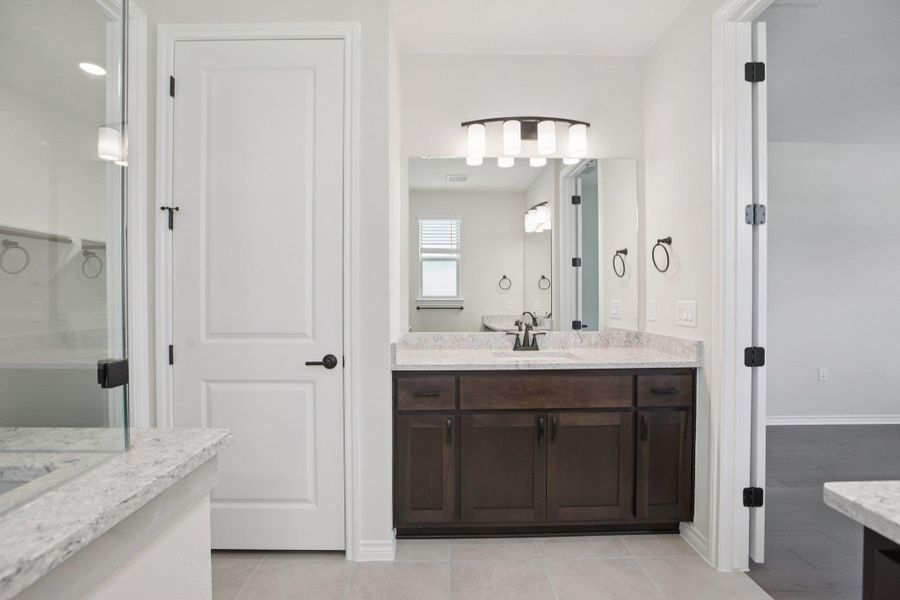 Full bathroom with two vanities, light tile patterned flooring, and a shower stall