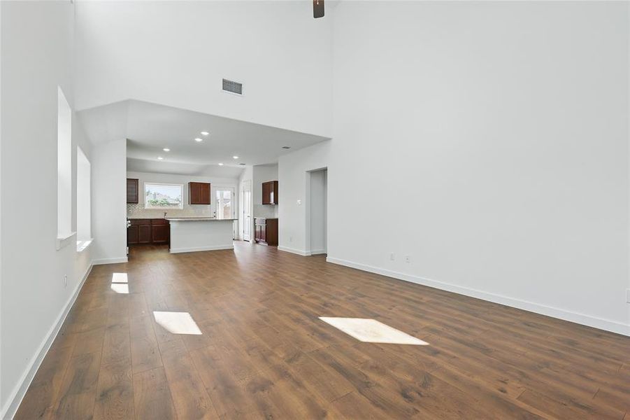 Unfurnished living room featuring dark wood finished floors, recessed lighting, and a high ceiling