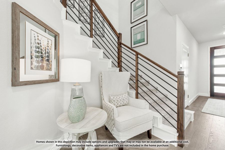 Entryway with staircase featuring wood and metal railings, white walls, hardwood floors, and a sitting area with accent chair. Entryway with staircase featuring wood and metal railings, white walls, hardwood floors, and a sitting area with accent chair.