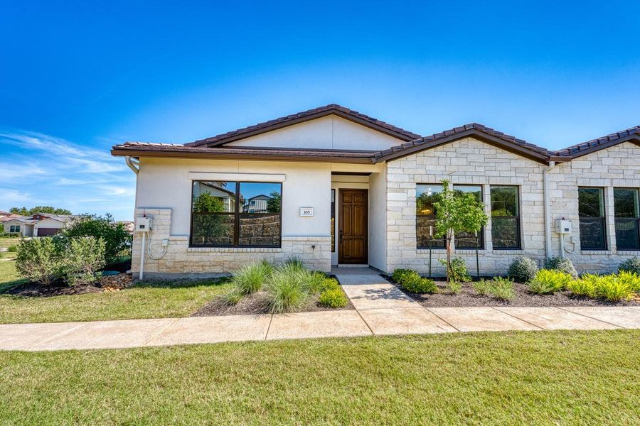 View of front of property featuring stone siding, a front lawn, a tiled roof, and stucco siding