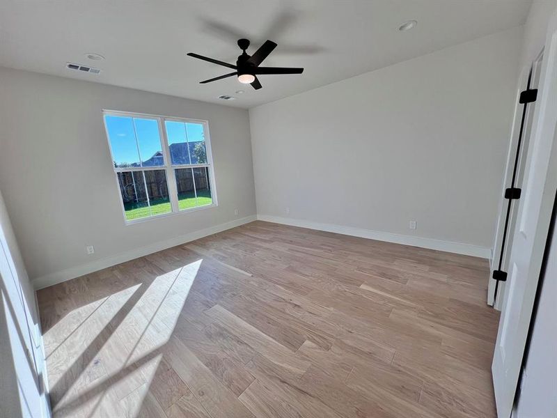 Master bedroom with wood floor, can lights and ceiling fan.