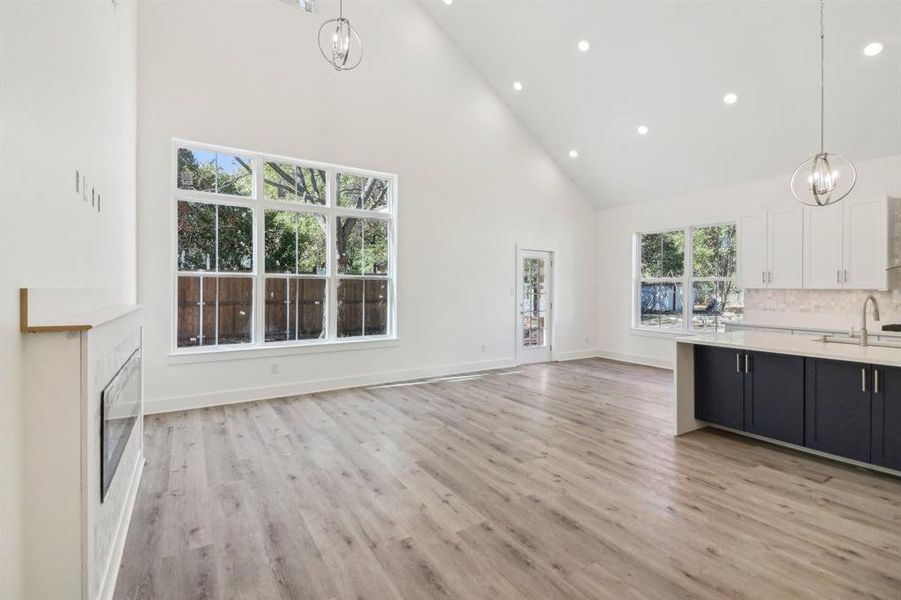 Kitchen featuring high vaulted ceiling, a chandelier, pendant lighting, recessed lighting, and white cabinets