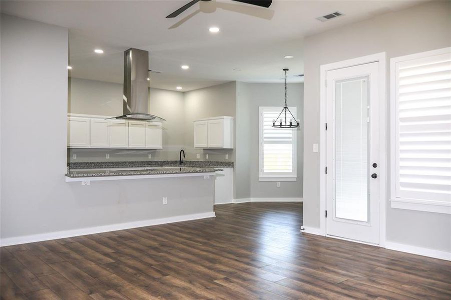 Kitchen featuring dark wood-type flooring, white cabinets, island range hood, a peninsula, and recessed lighting Kitchen featuring dark wood-type flooring, white cabinets, island range hood, a peninsula, and recessed lighting