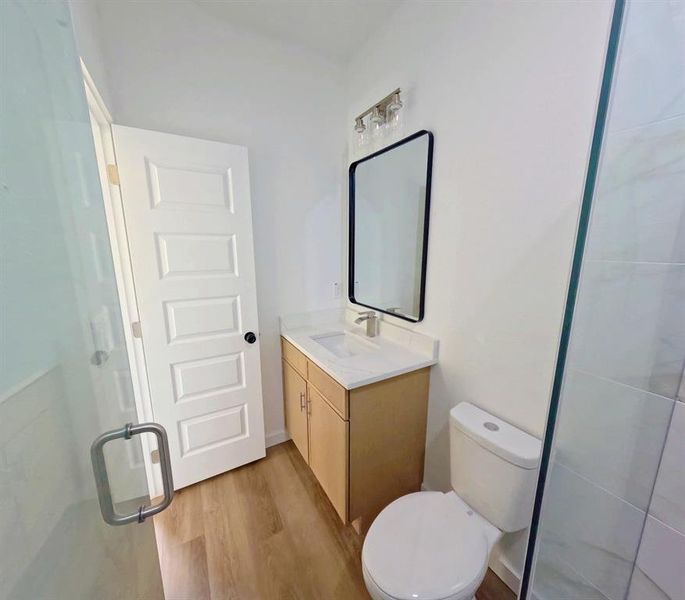 Full bath featuring light wood-type flooring, vanity, and a stall shower Full bath featuring light wood-type flooring, vanity, and a stall shower