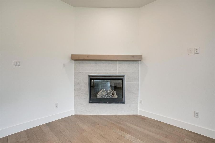 Details with a tiled fireplace and hardwood / wood-style floors