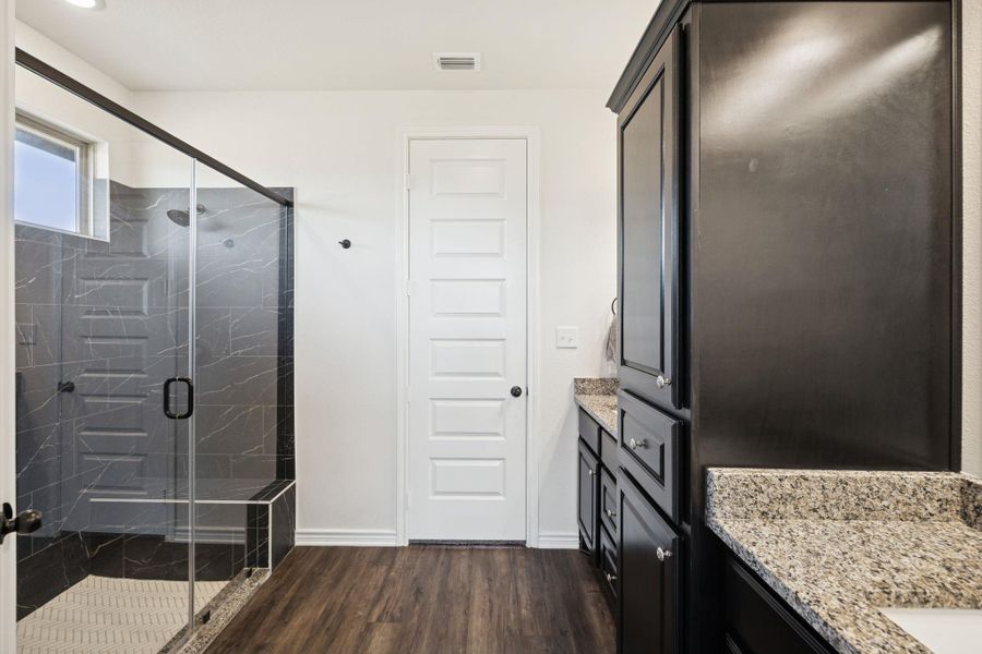 Full bathroom featuring vanity, dark wood-style floors, and a marble finish shower Full bathroom featuring vanity, dark wood-style floors, and a marble finish shower