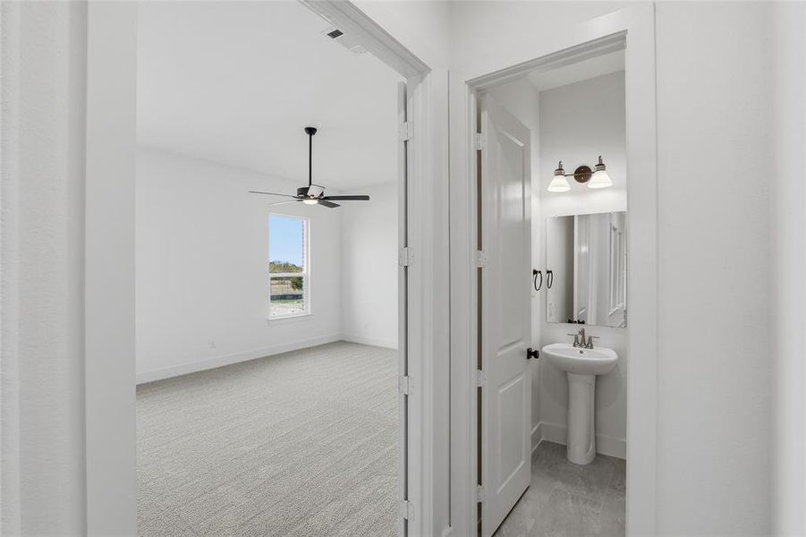Hallway featuring light colored carpet and baseboards
