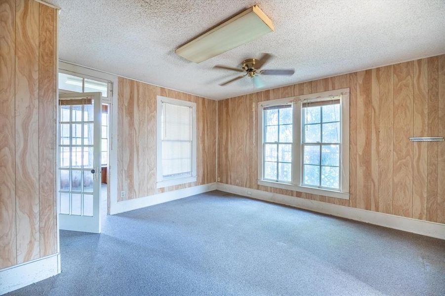 Unfurnished room featuring ceiling fan, wood walls, and a textured ceiling