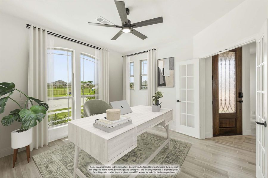 Home office with white desk, ceiling fan, large windows, and wood-look tile floors near front entry door Home office with white desk, ceiling fan, large windows, and wood-look tile floors near front entry door