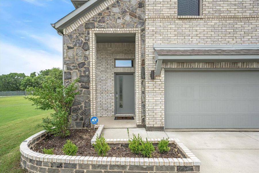 View of exterior entry featuring a garage and a yard