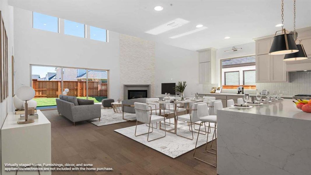 Living room featuring a towering ceiling, a large fireplace, plenty of natural light, and dark wood-type flooring