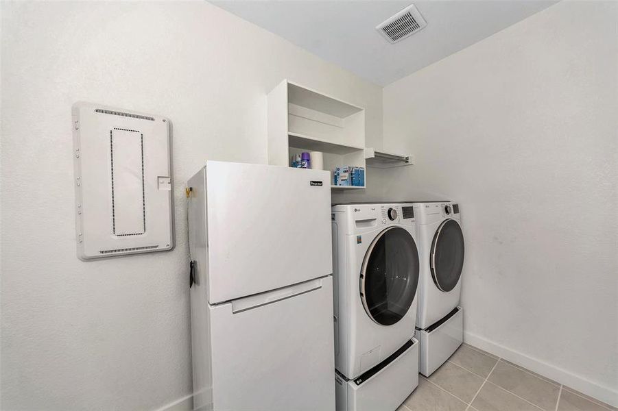 Laundry room with independent washer and dryer and light tile patterned floors