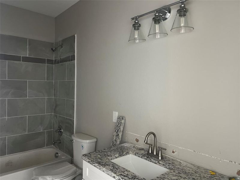 Full bathroom featuring vanity, tiled shower / bath combo, and toilet