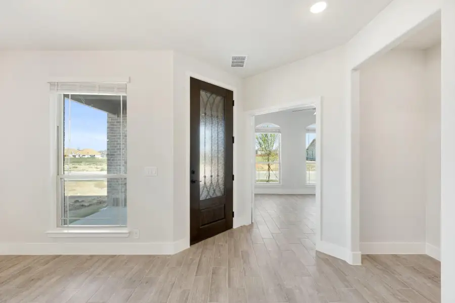 Home entryway with dark wood front door featuring glass panel, light tile floors, and white walls