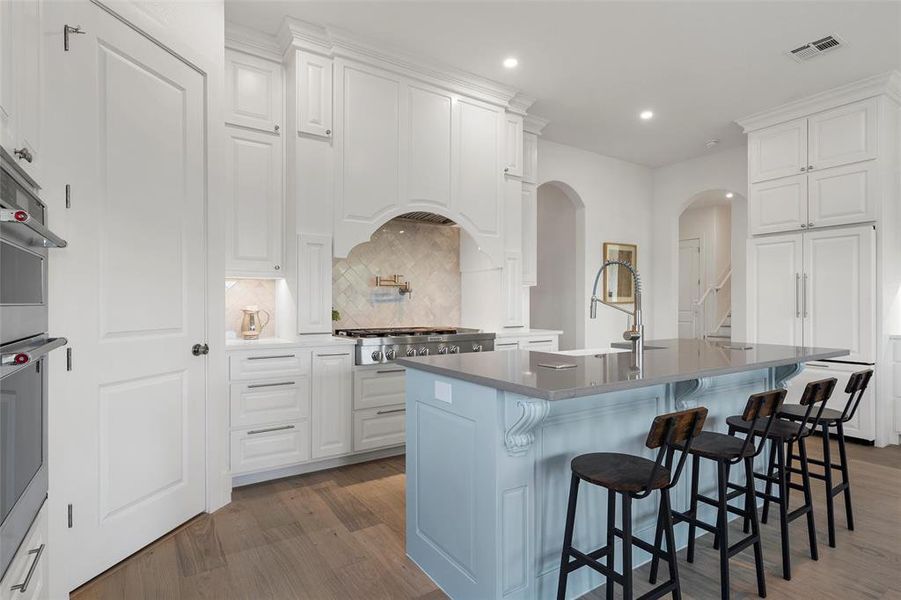Kitchen with tasteful backsplash, white cabinets, dark wood finished floors, a breakfast bar area, and an island with sink Kitchen with tasteful backsplash, white cabinets, dark wood finished floors, a breakfast bar area, and an island with sink