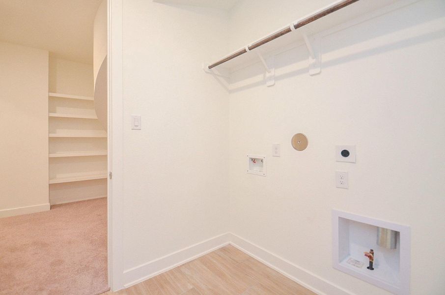 Dedicated utility room with built-in shelving, electric and gas dryer connections, and washer hookup.