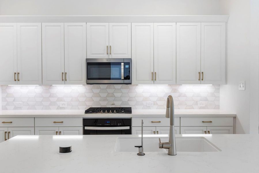 Beautiful backsplash and stylish hardware add a polished, modern touch to the kitchen.