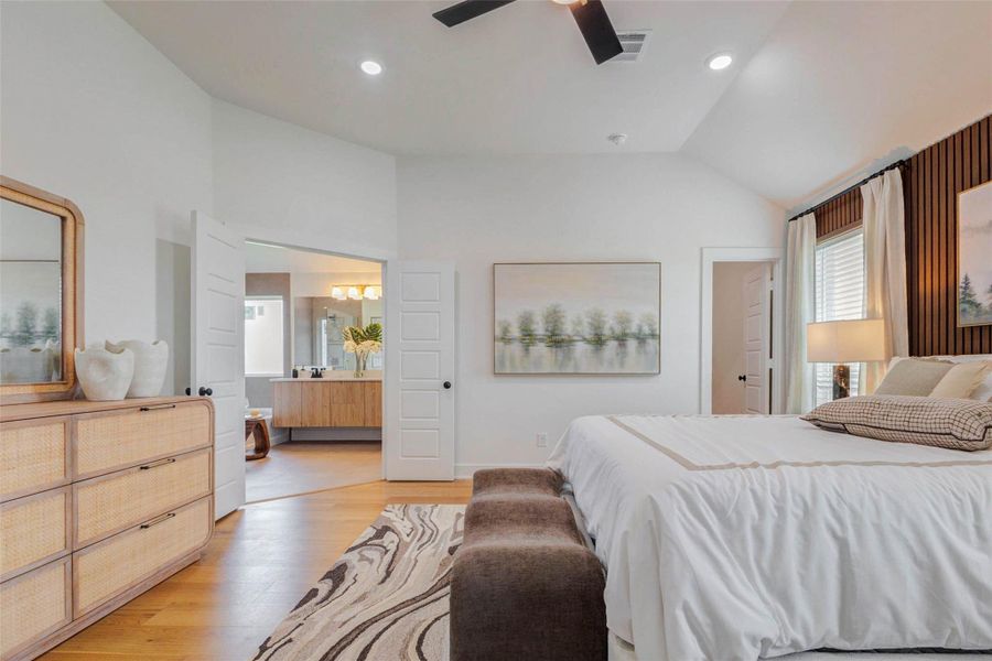 Another view of the primary suite highlights its generous size and seamless connection to the ensuite bathroom. The open doorway leads to a spa-inspired bath, enhancing both convenience and luxury. Soft tones, natural light, and elegant finishes create a serene environment, making this space a true private retreat within the home. The picture shown is from the model home with the same floor plan, Rev floor plan.