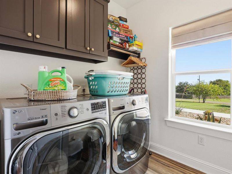 Laundry room with wood finished floors, cabinet space, and washing machine and clothes dryer
