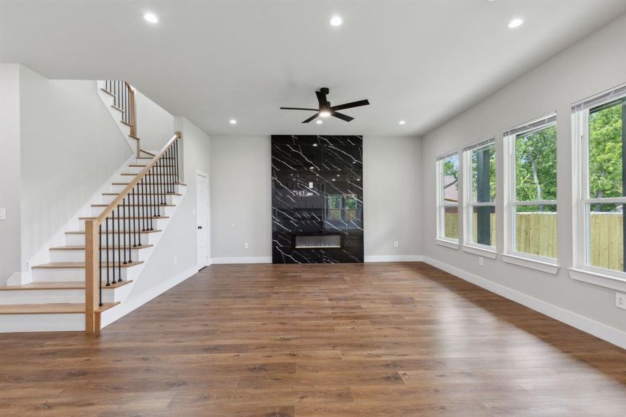 Unfurnished living room with hardwood / wood-style flooring, a wealth of natural light, and a premium fireplace