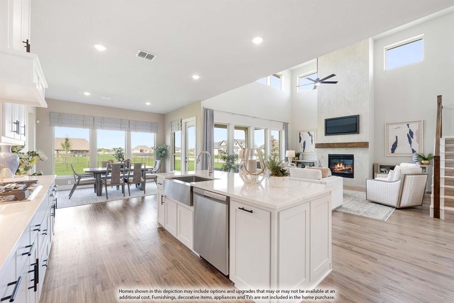 Open-concept kitchen with white island, quartz countertops, and hardwood floors flowing into living and dining areas with fireplace.