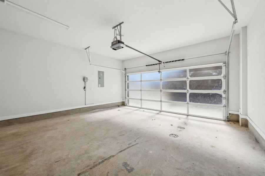 Garage featuring a garage door opener and electric panel