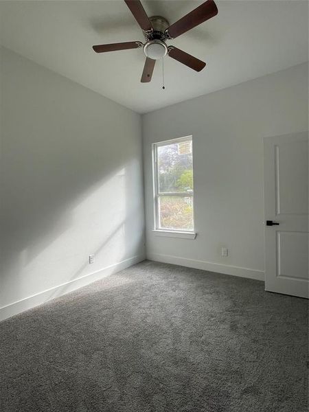 Empty room featuring dark carpet and ceiling fan