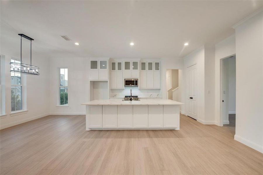 Kitchen with white cabinetry, an island with sink, glass insert cabinets, light wood-style floors, and recessed lighting