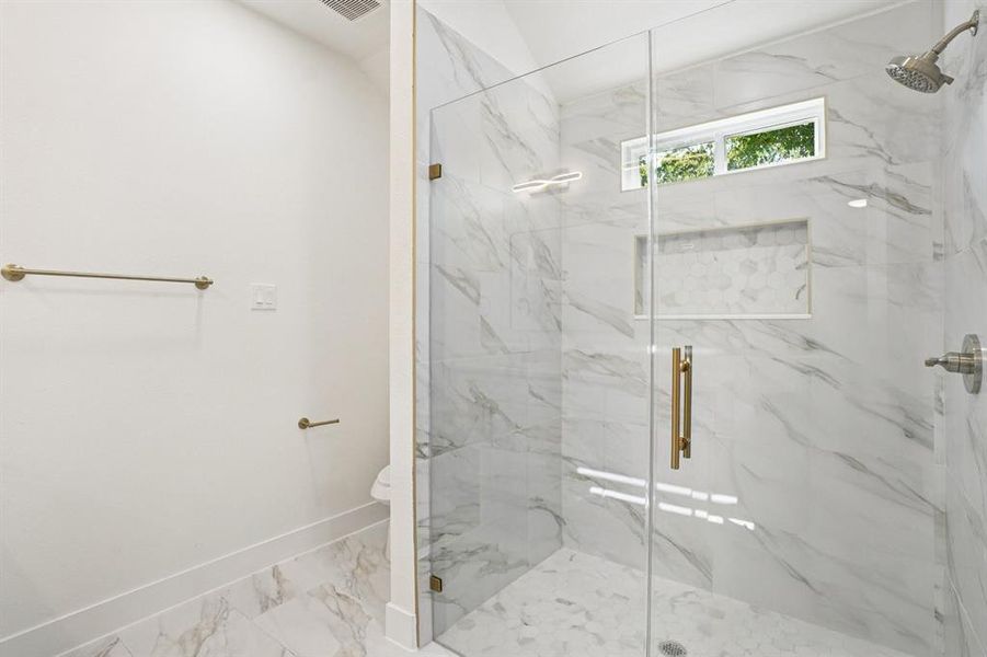Bathroom featuring a marble finish shower and marble finish floors Bathroom featuring a marble finish shower and marble finish floors