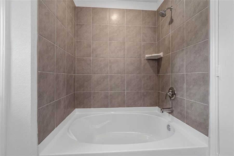 This primary bathroom features an oversized tub/shower combination with tile surround.