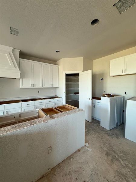 Kitchen featuring white cabinets, unfinished concrete flooring, and a textured ceiling