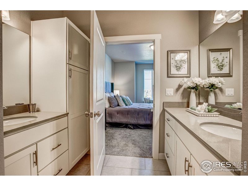 Primary bathroom w/ separate vanities + linen storage.