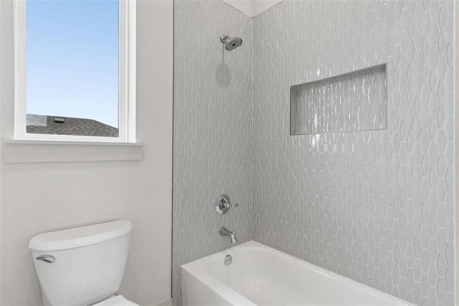 Bathroom featuring a white ceramic toilet, a white bathtub, and a shower with elongated hexagonal tile work Bathroom featuring a white ceramic toilet, a white bathtub, and a shower with elongated hexagonal tile work