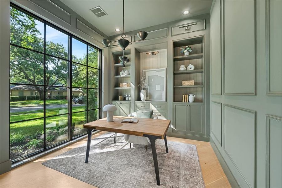 Interior space featuring extensive built-in shelving, panel-molded walls, and light wood-finish flooring