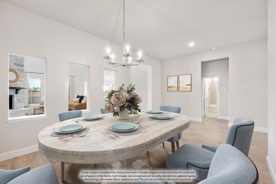 Dining room with oval wood table, blue chairs, chandelier, and vaulted ceiling over light hardwood floors