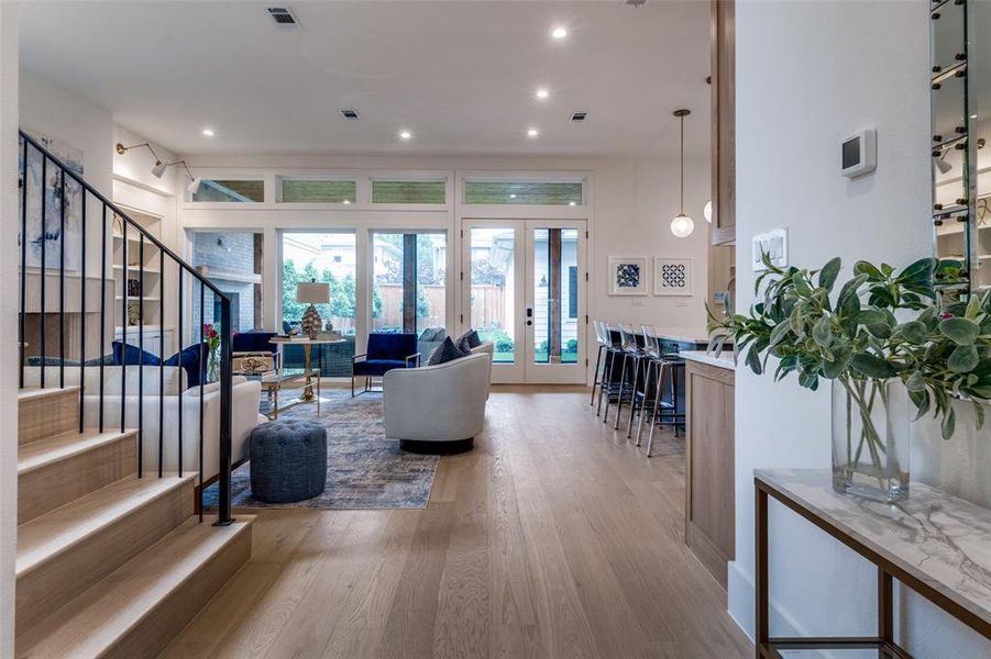 Living area with french doors, recessed lighting, visible vents, wood finished floors, and stairway Living area with french doors, recessed lighting, visible vents, wood finished floors, and stairway
