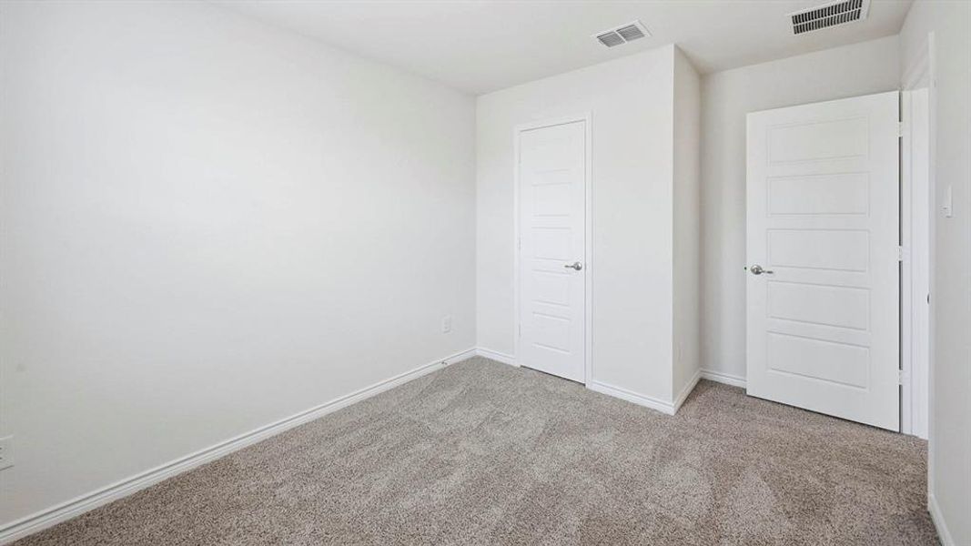 Interior room featuring neutral wall paint, gray carpet flooring, white trim, and two white paneled doors with chrome hardware
