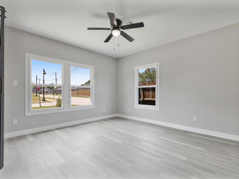 Unfurnished room featuring light wood-type flooring, healthy amount of natural light, baseboards, and a ceiling fan