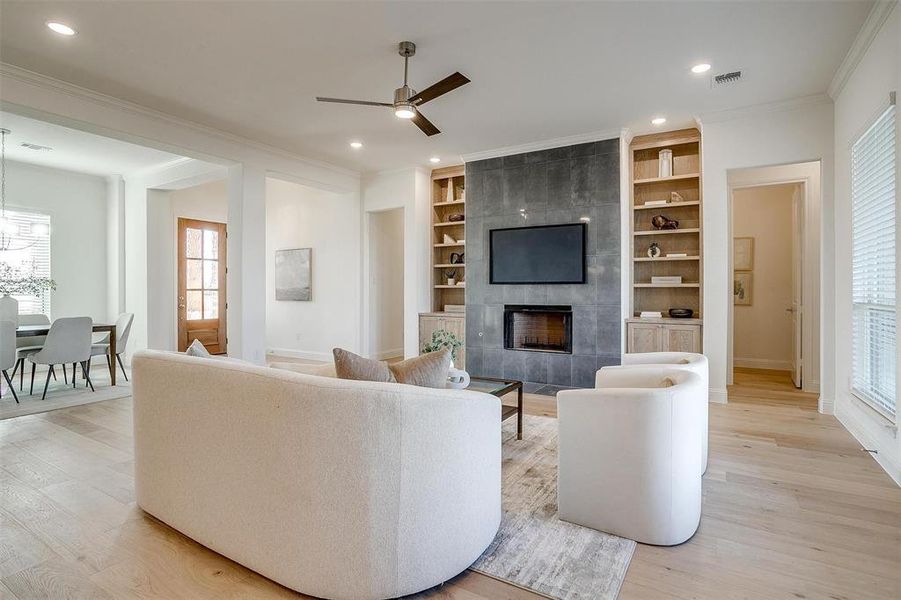 Living room featuring a fireplace, ceiling fan, light hardwood / wood-style flooring, and built in shelves