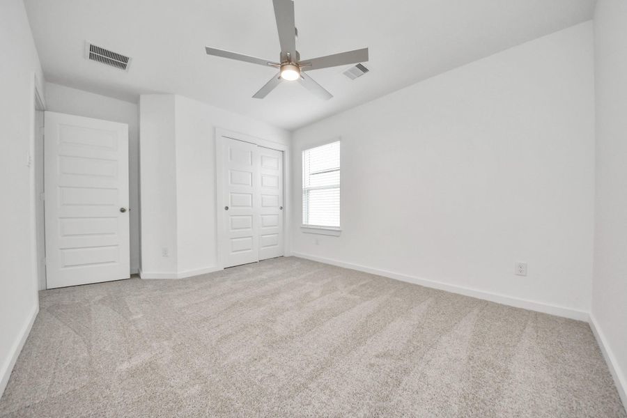 Secondary bedroom features plush carpeting, large windows that let in plenty of natural light, bright paint, and spacious closets. Sample photo of completed home with similar floor plan. Actual colors and selections may vary. Secondary bedroom features plush carpeting, large windows that let in plenty of natural light, bright paint, and spacious closets. Sample photo of completed home with similar floor plan. Actual colors and selections may vary.