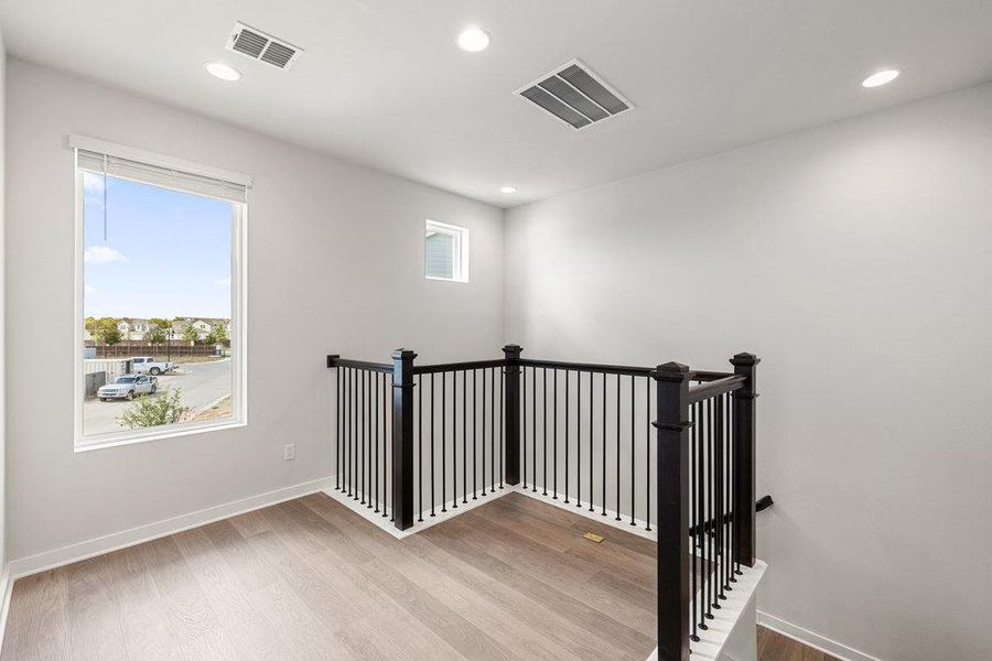 Stairway featuring plenty of natural light, wood finished floors, and recessed lighting