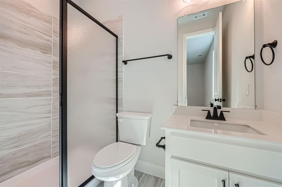 Bathroom featuring vanity, toilet, and an enclosed shower