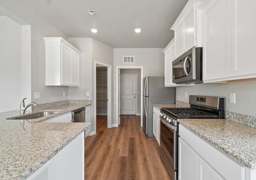 The kitchen has stainless steel appliances and plank flooring.