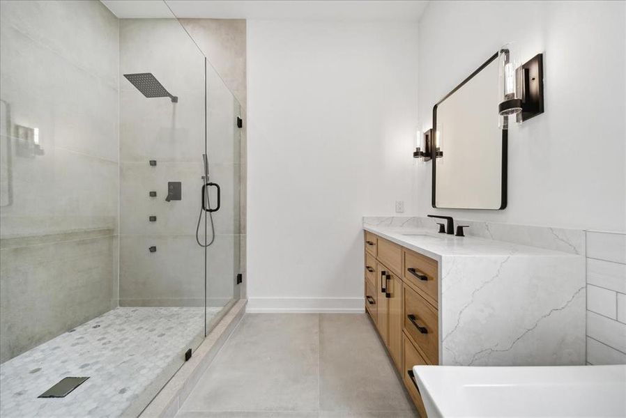 Bathroom featuring tile patterned flooring, walk in shower, and vanity