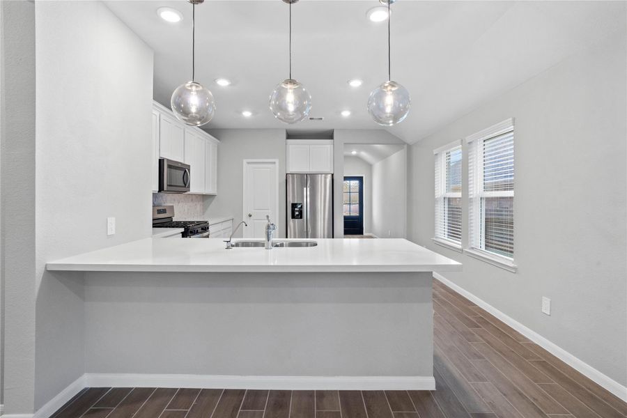 The expansive quartz-topped counter stands as the home's true heartbeat, offering a natural gathering spot where family and friends naturally gravitate to share meals, conversation, and connection.