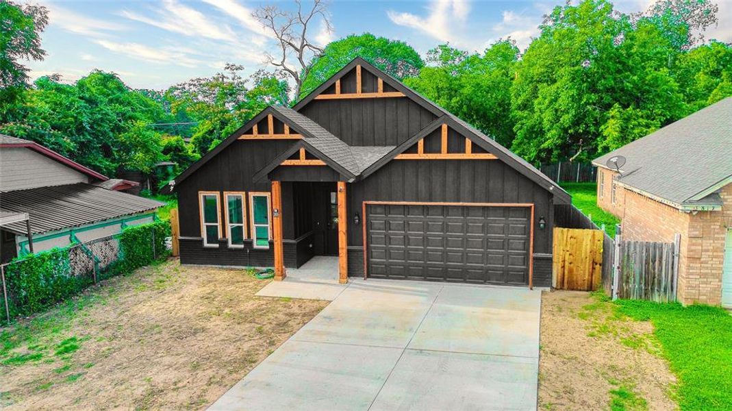 View of front of property featuring an attached garage, concrete driveway, board and batten siding, and roof with shingles
