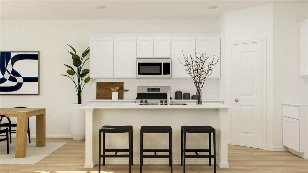 Kitchen with white cabinets, an island with sink, backsplash, appliances with stainless steel finishes, and light wood-type flooring