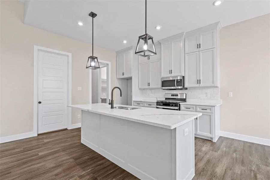 Kitchen with a center island with sink, white cabinetry, appliances with stainless steel finishes, and sink